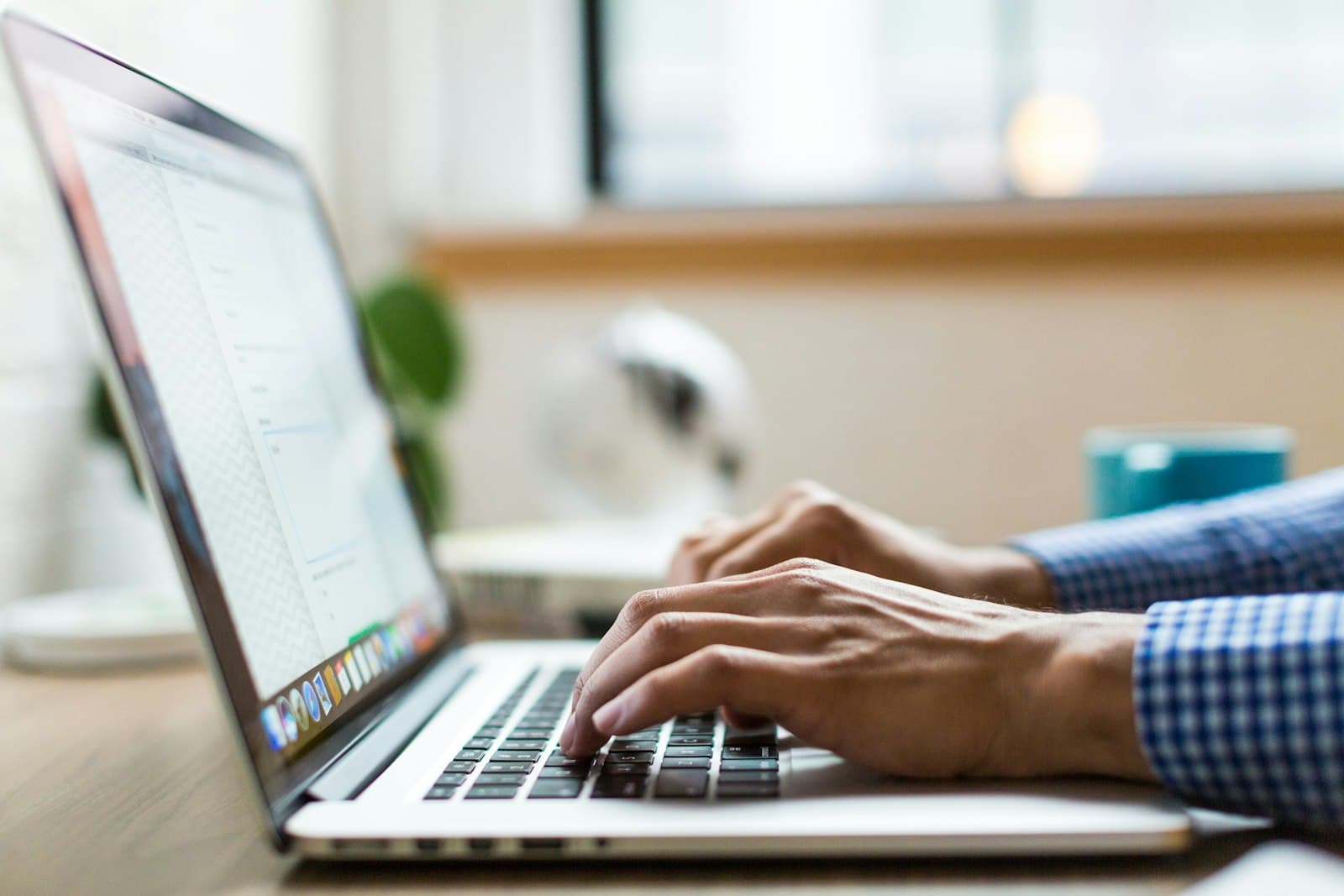 An anonymous pair of hands typing a search on a laptop keyboard in low light.